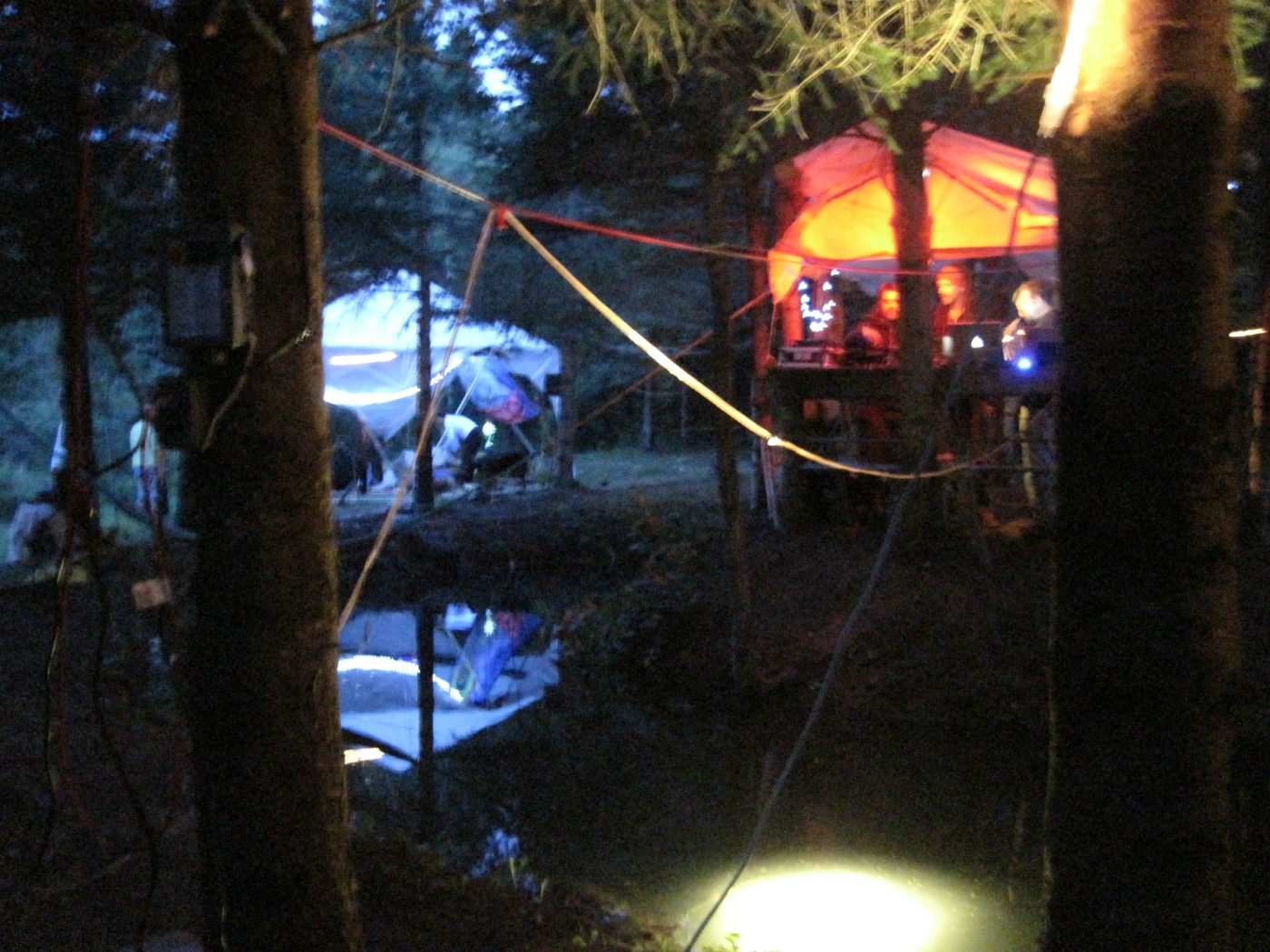 Les tentes et les lumières se reflètent dans l'eau.