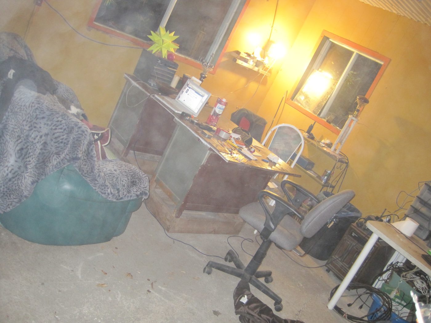 Le bureau, installé dans un coin : ordinateur, filet, plante.