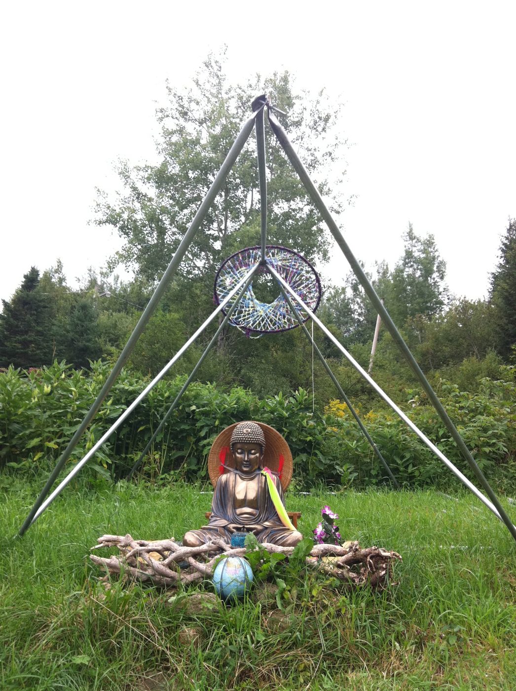 Le bouddha sous son tripode, dans l'herbe.